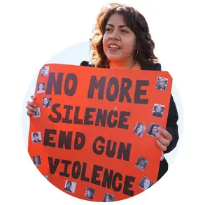 Woman holding a sign that says "no more silence end gun violence"