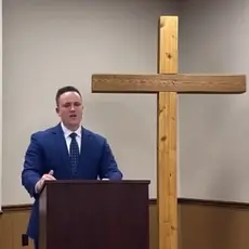 Ben Zeisloft speaking in front of a cross