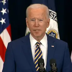 President Biden giving a speech in front of a pair of American flags