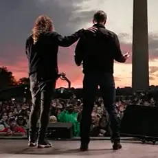 Photo from behind Sean Feucht and Josh Hawley with crowd in front of them and Washington monument behind the crowd. 