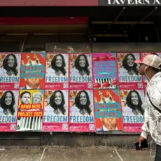 A man walks by a wall of posters of Kamala Harris that say Freedom