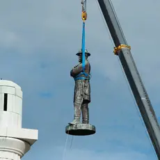 A state of Robert E. Lee is removed by a crane from its perch.