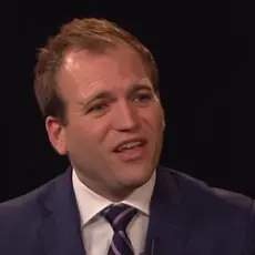 Image taken from video: Johnnie Moore in suit and tie against dark background, speaking to off-camera CBN hosts.