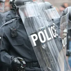 A group of police in riot gear with riot shields.