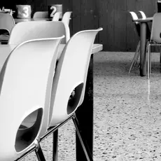 A black and white image of school tables and chairs.