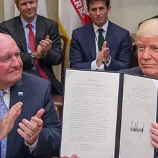 Agriculture Secretary Sonny Perdue with Trump holding up a signed executive order.