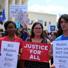 three people holding pfaw signs at a rally in front of supreme court