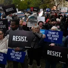 A group of people holding signs that say "Trump is not above the law" and "Resist"