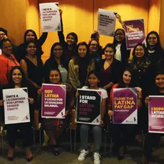 A group of people holding signs that say "Close the Latina pay gap" "I support Latina workers" and "Soy latina"