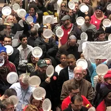 A crowd of people hold paper plates in a rally