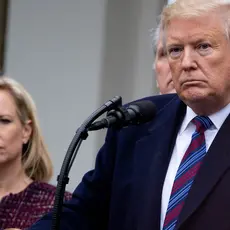 Donald Trump stands at a podium with Kirstjen Nielson