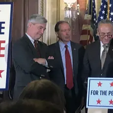 Amy Klobuchar stands at a podium next to Sens. Whiteshouse, Schumer, and Merkley to introduce the For the People Act