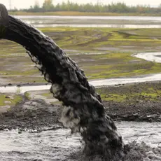 A pipe dumps grey sludge into the environment