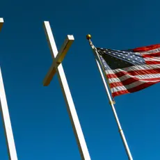 The American flag waves next to three large crosses