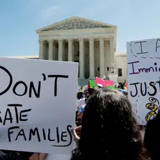 Rally-goers in front of the Supreme Court holding signs that say "Don't separate families" and "I am immigrant justice"