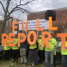 A group of people in neon yellow shirts holding letters that spell 'FULL REPORT"