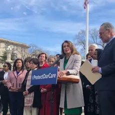 Nancy Pelosi speaks at a podium in front of a group of people.