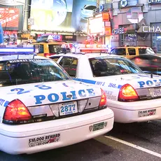 Two police cars drive side-by-side down a busy street