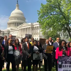 Activists stand outside the U.S. Capitol Building and hold signs that support Brown v. Board