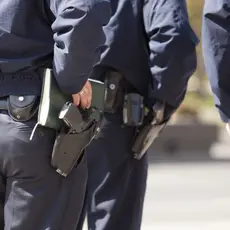 A close-up of police officers waists with guns on their hips