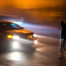 A person crosses the street in front of a car.