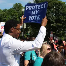 Activists hold signs that say "Every person counts" and "Protect my Vote"