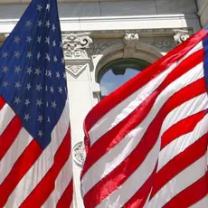 picture of two American flags against a white building