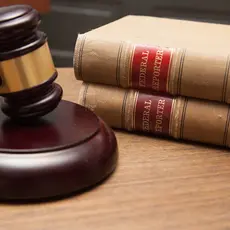 Judge's gavel in a courtroom, stack of law books.