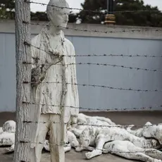 An art instillation depicting bodies laying on the ground and one man holding onto a barbed wire fence at the Holocaust Museum