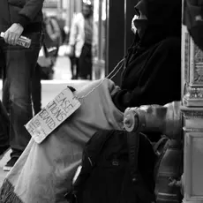 homeless man sitting on street with sign