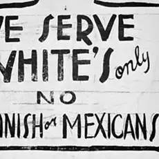 An old sign with the text "We serve white's only. No Spanish or Mexicans."