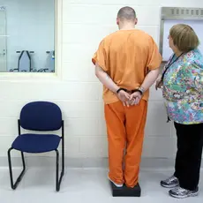 A nurse measures a prisoner's weight