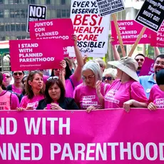 Protesters in Chicago wearing pink and carrying signs that say "I stand with Planned Parenthood."