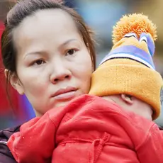 A woman holds her toddler in her arms.