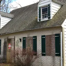 A boarded up house with a notice on the front door.