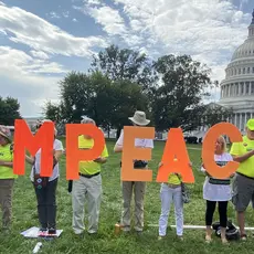 A line of activists in from of the U.S. Capitol Building holding the letters of the word "IMPEACH"