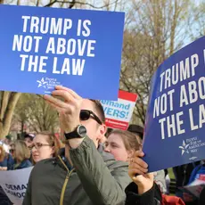 Activists hold signs saying "Trump is not above the law."