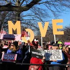 A group of rally-goers hold signs stating "Impeach now," "Impeach," and "No one is above the law" outside the Capitol Building in December 2019.