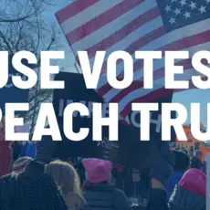 Rally-goers hold signs demanding the impeachment of Trump