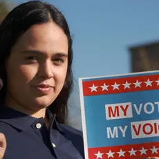 A woman holds a sign that says "My vote, my voice."