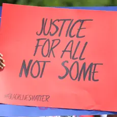 At a Black Lives Matter protest, a sign reads "Justice for All, Not Some."