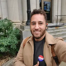 Svante Myrick standing outside a courthouse displaying an "I Voted" sticker.