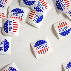 Stickers reading "I voted" are scattered on a white surface.