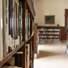 A school library bookshelf with a table in the background.