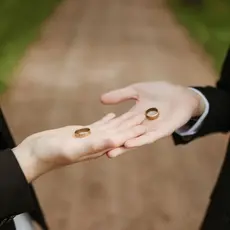 Two hands each holding a wedding ring in their palms.