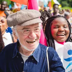 A grandparent smiling at a rally with younger people.