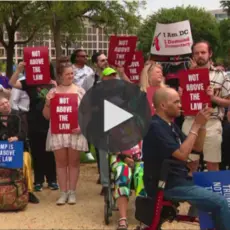 A group of people standing outside holding signs that read "Not Above the Law"