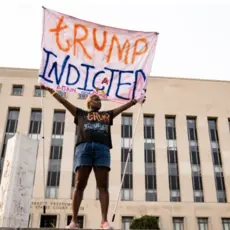 A protester displays a sign outside of the E. Barrett Prettyman U.S. District Court House in Washington, D.C., on Tuesday, Aug. 1, 2023. Members of a grand Jury met to examine former President Donald Trump’s role in the Jan. 6 riot and effort to overturn the 2020 election.