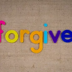 Colorful letters on a wood background. Letters spell "forgive"