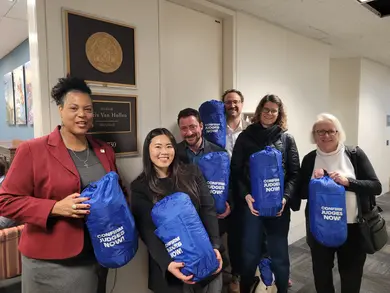 A group of people hold sleeping bags in the Senate office building.